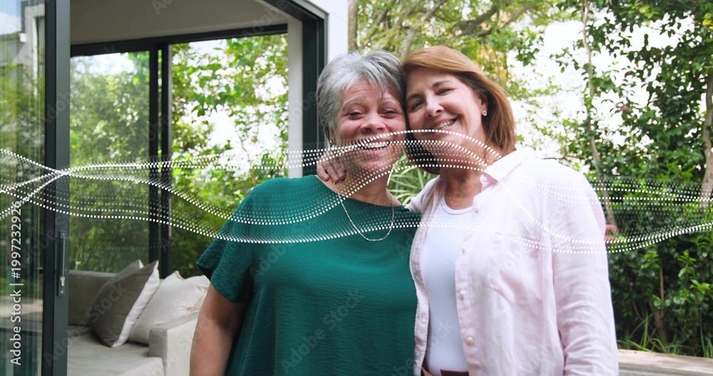 Fototapeta premium Smiling mom and daughter posing on patio by sliding door, green, pink tops, white dotted overlay