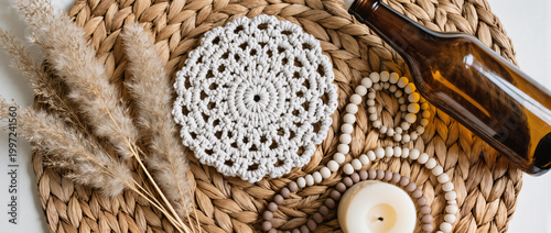 Boho Decor Flatlay with Macrame Coaster, Pampas Grass, Amber Glass Bottle, Ceramic Beads and Neutral Candle on Woven Rattan in Soft Natural Light