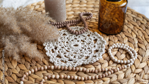 Boho Decor Flatlay with Macrame Coaster, Pampas Grass, Amber Glass Bottle, Ceramic Beads and Neutral Candle on Woven Rattan in Soft Natural Light