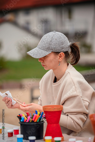 Focused young woman cleaning paint brush with paper towel during outdoor craft workshop
