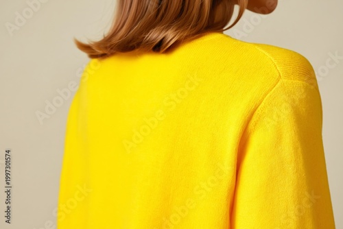 Smiling Woman in Yellow Sweater Poses in Studio Setting With Neutral Background