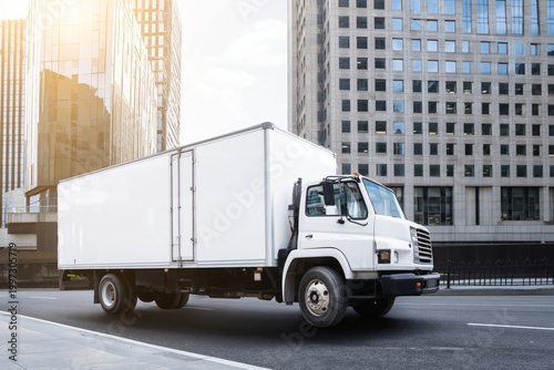 Delivery Truck Driving on Urban Road Next to Modern Buildings at Sunset