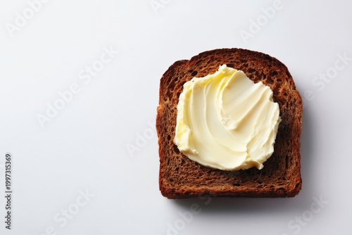Butter Spread on a Slice of Brown Bread Sitting on a Plain Surface