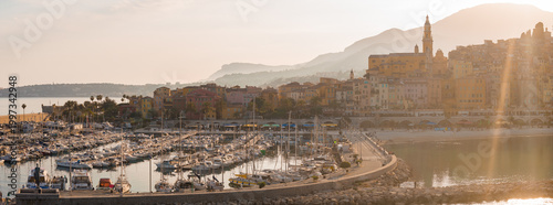 Konstfotografi Aerial view of Menton, France shows the old town on the right, the marina of white hull boats along the breakwater, and the Basilica of Saint Michel by the layered hills