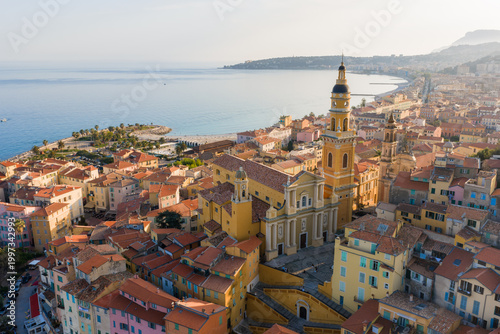 Aerial view of Menton, France, old town and Basilica of Saint Michel by the Baie de Garavan, marina left, terracotta roofs, late afternoon light, Mediterranean Sea.