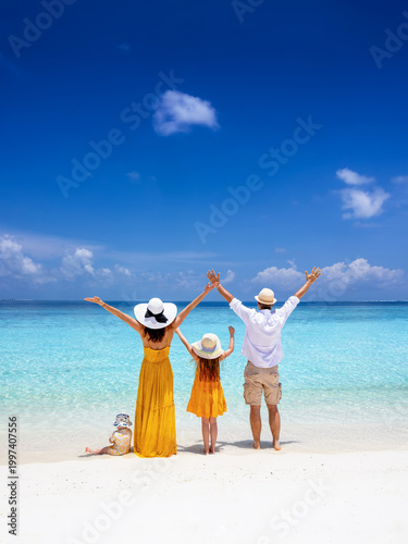 Canvas Print A happy family stands on a tropical paradise beach with turqouoise sea and fine