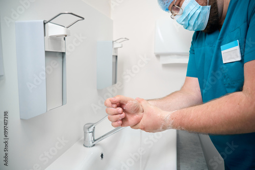 Caucasian man washing hands in medical facility restroom