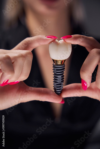 Female adult holding dental implant indoors with soft lighting