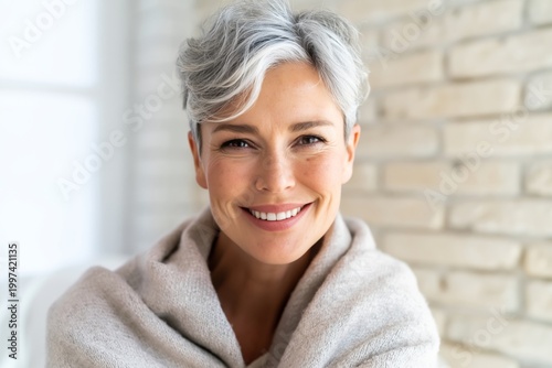 Woman Smiles While Wrapped in a Blanket in a Cozy Room With Natural Light Dur...