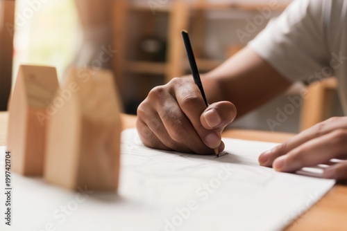 Hand Drawing Design Plans for Wooden Models on a Table in a Workshop