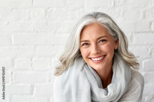 Smiling Woman With Light Gray Hair in Front of a White Brick Wall During Daytime