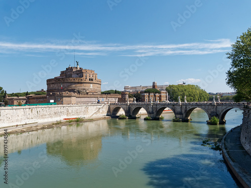 View of Castel Sant'Angelo and Ponte Sant'Angelo reflected in the Tiber River, Rome, Italy, on a clear spring day with blue sky