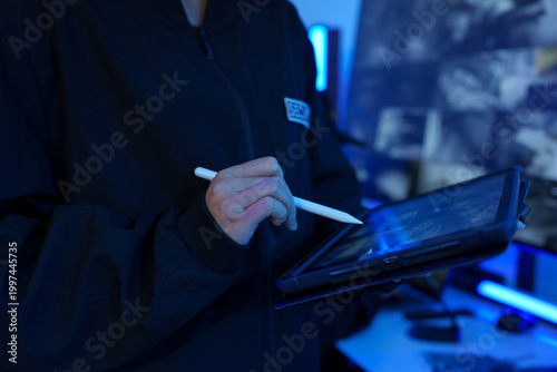 Focus on the iPad in the hand of the security guard checking the CCTV TV screen.	