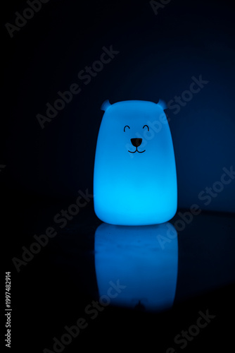Bear shaped glowing night light lamp in dark background.