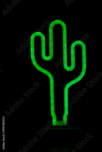 Green neon cactus lamp glowing in dark background.