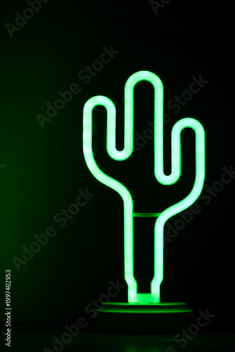 Green neon cactus lamp glowing in dark background.