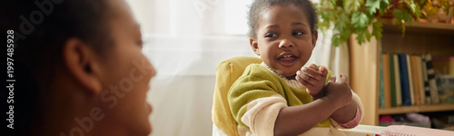 Φωτογραφία Website header shot of Black child sitting with mother, gesturing during home conversation, showing low income family life