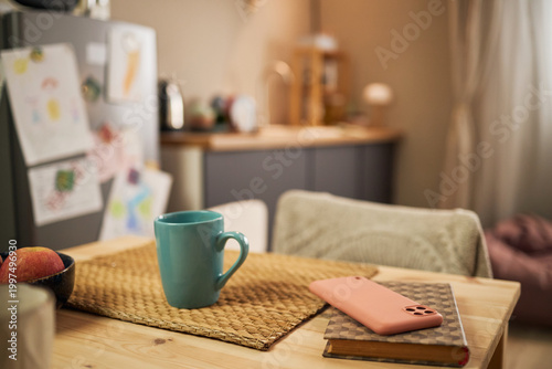 Картината върху платно Close up of family kitchen table showing mug, smartphone, notebook, fruit, suggesting low income household routine and budgeting