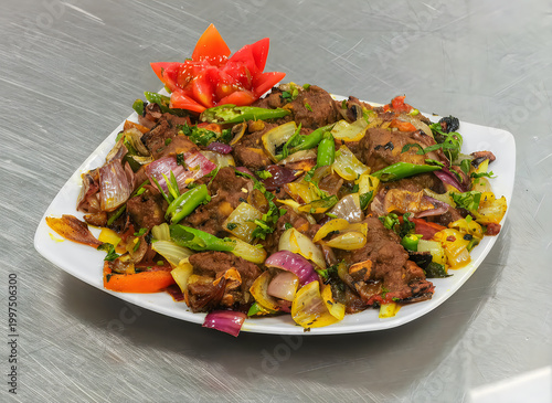 Plate of stir-fried vegetables with meat and colorful garnish on gray surface
