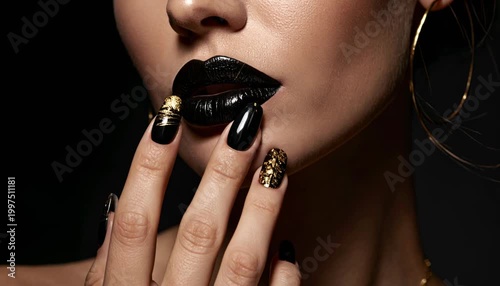 Elegant woman with dark lipstick and golden nail art touching her lips.