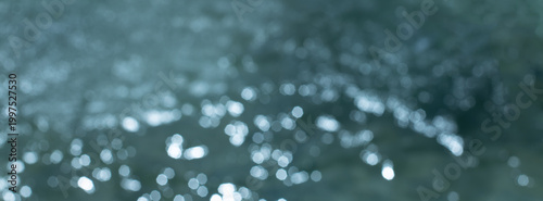 Soft teal bokeh of sparkling water reflections creating an abstract calm background