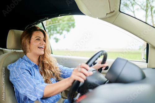 Happy woman driving convertible car on road trip