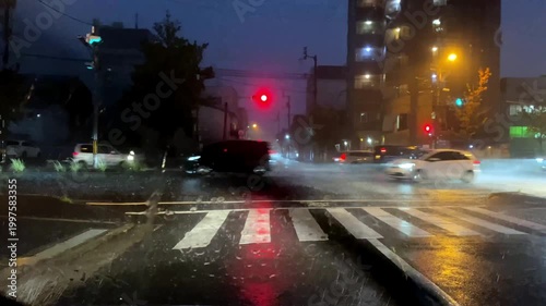 雨の夜の都市交差点を通る光跡と横断歩道の映像