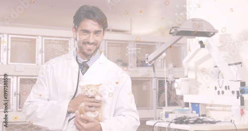 Obraz na plátně Cradling male vet holding orange tabby cat in vet exam room, coat, stethoscope,