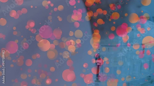 Gloved hand entering right, adjusting lid knob, tilting can into inlet loading vessel, bokeh rising