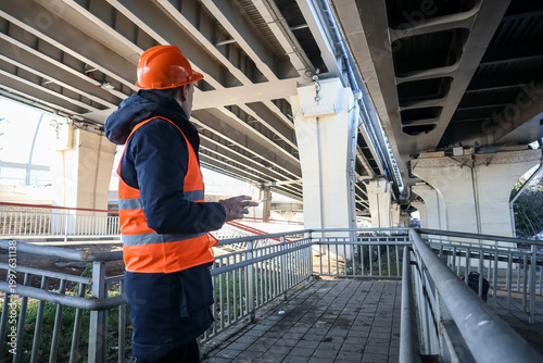 Engineer gesturing toward bridge supports during inspection