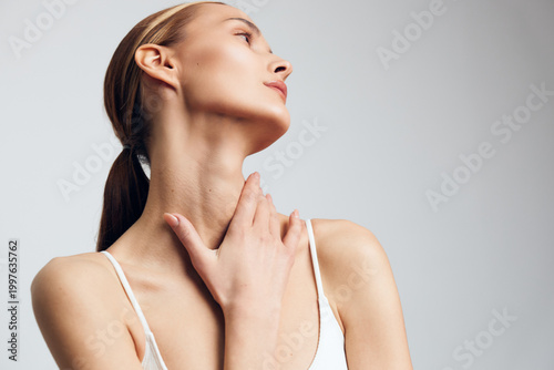 Tableau sur toile Woman skincare beauty portrait in studio lighting, she touches neck with both ha
