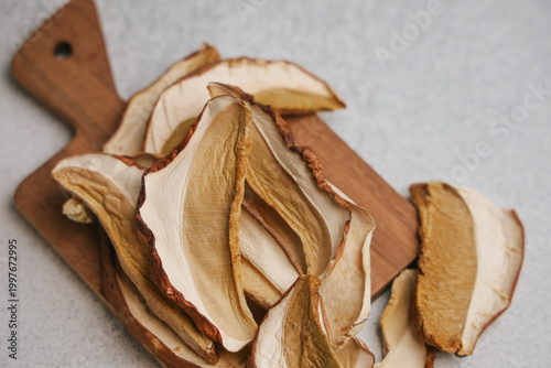Quadro su tela Dried mushrooms Boletus edulis on wooden cutting board next to kitchen surface i
