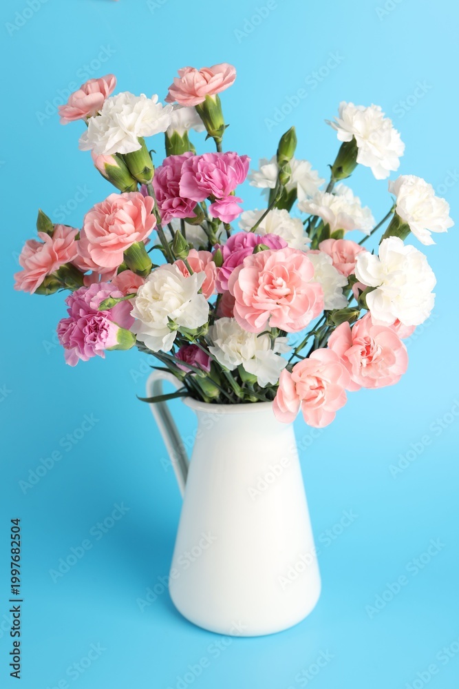 Fototapeta premium Beautiful carnation flowers in vase on light blue background, closeup