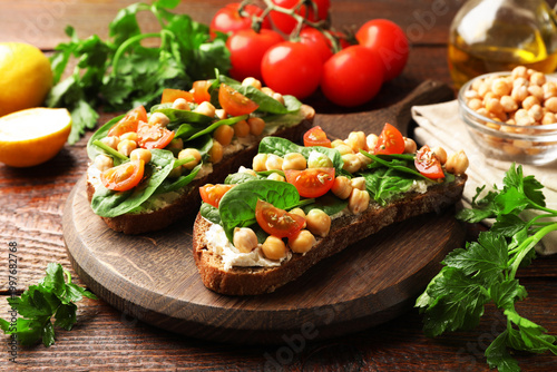 Tableau sur toile Delicious sandwiches with chickpeas and other ingredients on wooden table, close