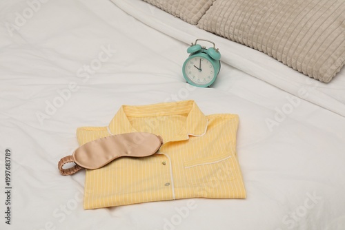 Konstfotografi Alarm clock, sleeping mask and pajamas on bed, closeup