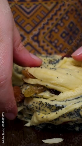 Woman hands rolling dough pastry with poppy seeds and raisins baking muffin style pastry closeup