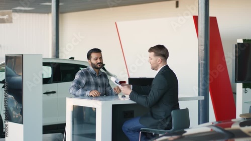 Indian customer signing a contract with car dealer in showroom