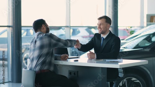 Successful car salesman making a deal and shaking hands with Indian client