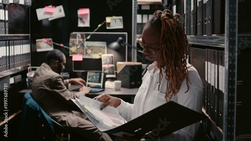 Tableau sur toile Private inspectors working with criminal records in police archive office, examining forensic evidence to find clues