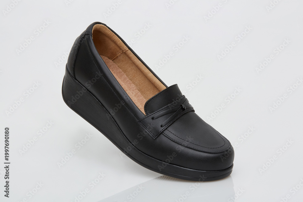 Fototapeta premium Comfort centered black leather wedge loafer for women with slip on design and cushioned insole, supportive platform sole, minimalist penny upper, studio product shot on light gray background
