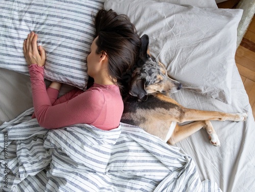 top view of sleeping woman and dog in bed. girl and pet sleep comfortably together and cuddle. happy owner wakes up next to his dog. rest in bathroom after hard day. dog training, insomnia treatment.