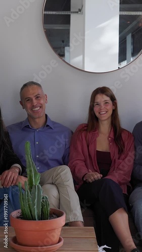 Diverse Caucasian business team sitting together at coworking office. Two professionals looking at camera while sitting on a modern sofa in a relaxed workspace. Business and teamwork concept.