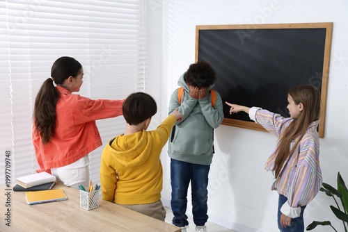 Fotografie African American boy getting bullied by his classmates in classroom