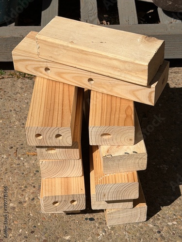 Stack of Reclaimed Pine Wood Blocks with Pre-Drilled Holes for DIY Upcycling Project on Concrete