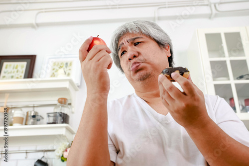 Fotografie The obese man appears to prefer the sugary donut over the apple, seemingly unconcerned about the risk of diabetes : Nutritional concepts for obese people