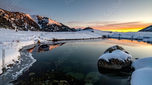 Snow-capped mountains reflect in a tranquil lake at dawn; a serene winter landscape