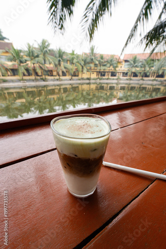 a Vietnamese coconut coffee, resting on a polished reddish-brown wooden table