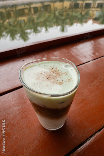 a Vietnamese coconut coffee, resting on a polished reddish-brown wooden table
