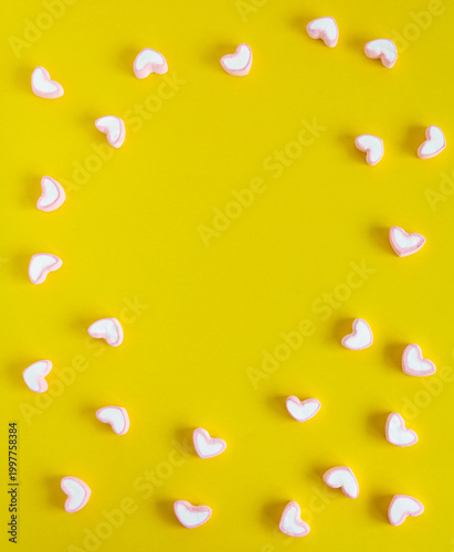 Small heart shapes scattered on a bright yellow background creating a playful and minimal composition.