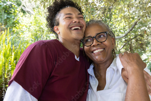 African American senior mother and son smiling in park, with glasses, maroon, light shirts